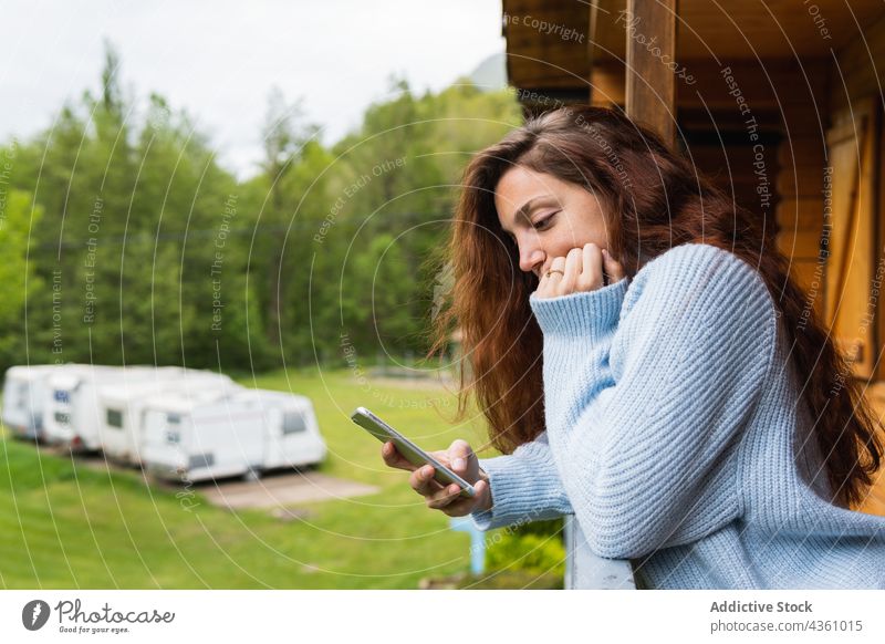 Nachdenkliche Frau, die auf der Terrasse eines Hauses auf ihrem Smartphone surft Berge u. Gebirge nachdenklich Urlaub reisen Reisender benutzend Pyrenäen