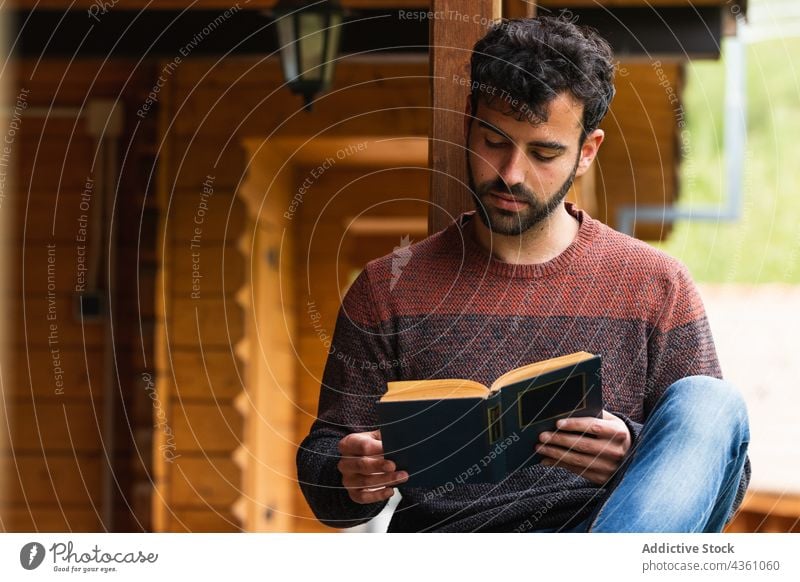 Nachdenklicher Mann auf Terrasse mit Buch lesen nachdenken nachdenklich Urlaub Haus Veranda Literatur männlich Pyrenäen ruhen sich[Akk] entspannen hölzern Kälte