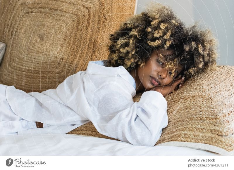 Nachdenkliche schwarze Frau auf dem Bett liegend im Schlafzimmer genießen ruhen positiv Komfort sich[Akk] entspannen Morgen Glück heimwärts froh sorgenfrei