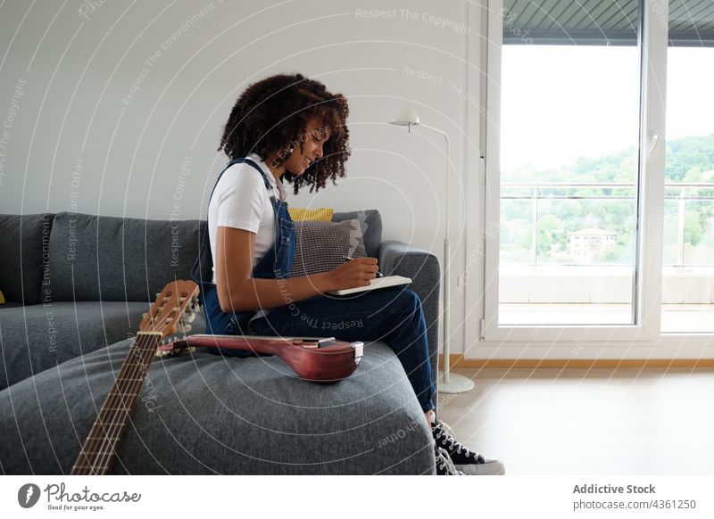Schwarzer Musiker komponiert Musik zu Hause Frau komponieren nachdenklich Notebook heimwärts besinnlich kreativ Notizblock ethnisch schwarz Afroamerikaner