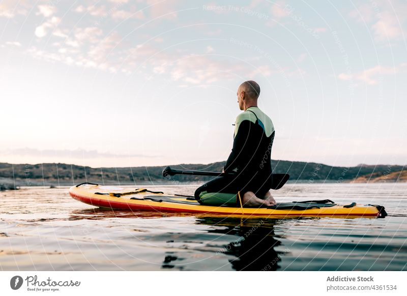 Mann übt Yoga auf SUP-Board im Meer Paddelbrett meditieren Zusatzplatine MEER üben Donnernde Pose Namaste Abend männlich Surfer Wasser Asana Sonnenuntergang