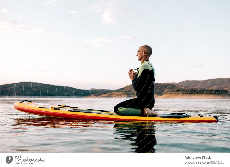 Mann übt Yoga auf SUP-Board im Meer Paddelbrett meditieren Zusatzplatine MEER üben Donnernde Pose Namaste Abend männlich Surfer Wasser Asana Sonnenuntergang