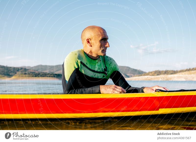 Mann übt Paddleboarding im Wasser eines Sees Paddel Holzplatte Lügen schwimmen Paddelbrett Aktivität üben Wassersport sportlich ruhen Schwimmer männlich aktiv