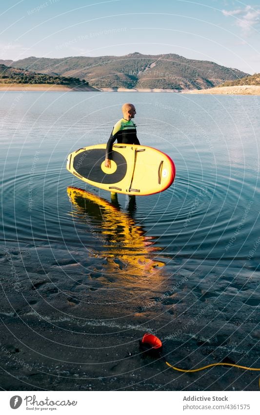 Mann mit Paddleboard im Meerwasser Paddelbrett MEER Zusatzplatine Neoprenanzug Surfer Surfbrett Wasser Sport männlich Aktivität Hobby aktiv Schwimmer stehen