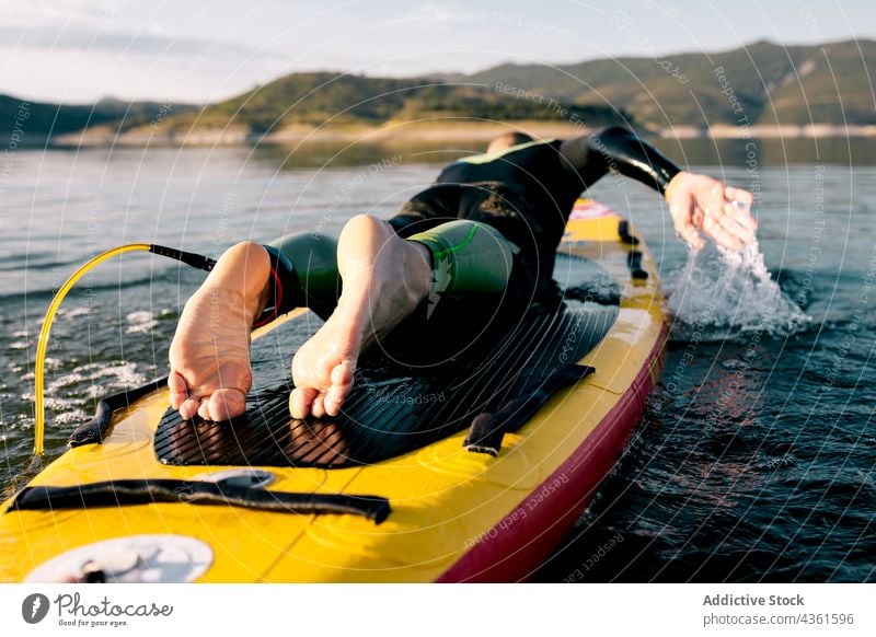 Mann übt Paddleboarding im Wasser eines Sees Paddel Holzplatte Lügen schwimmen Paddelbrett Aktivität üben Wassersport sportlich Schwimmer männlich aktiv