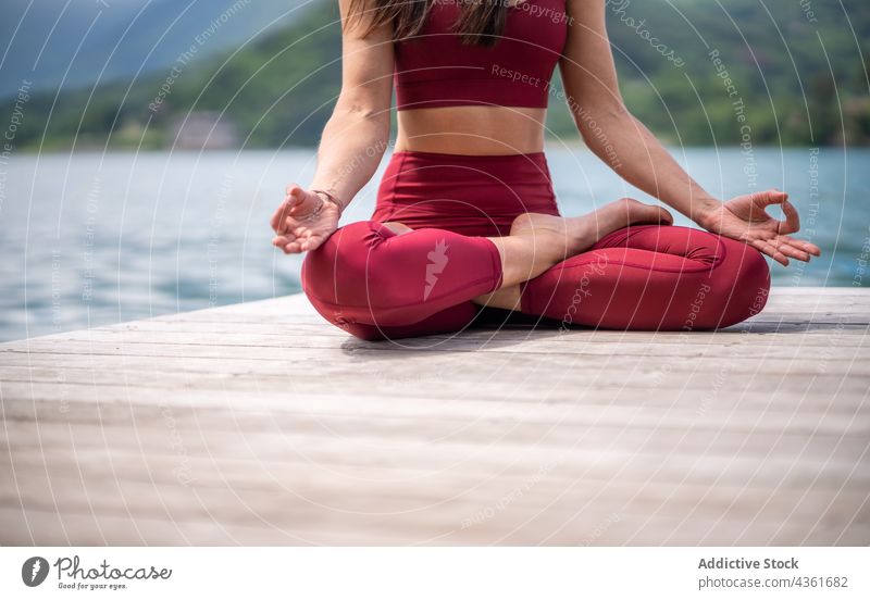 Flexible Frau meditiert in Lotus-Pose auf dem Pier meditieren Yoga padmasana See Gelassenheit üben Asana gestikulieren Wasser Gesundheit Mudra sitzen Vitalität