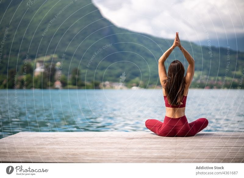 Anonyme flexible Frau meditiert in Lotus-Pose auf dem Pier meditieren Yoga padmasana See Gelassenheit üben Asana Wasser Gesundheit Mudra sitzen Vitalität