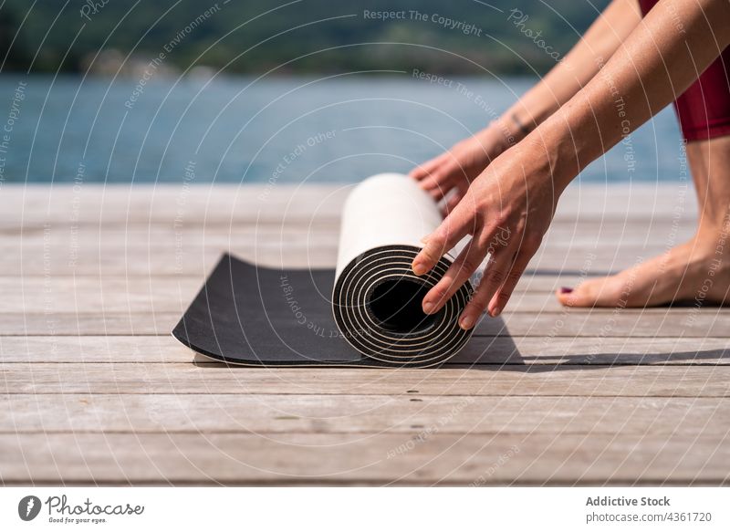 Schlanke anonyme Frau, die sich auf die Ausübung von Yoga am Pier vorbereitet Unterlage vorbereiten See schlank Erholung Sommer üben Wasser hölzern Kai Natur