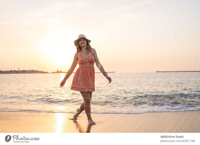 Junge Frau hat Spaß am Strand bei Sonnenuntergang Sommer MEER Glück sorgenfrei Spaß haben Stil Urlaub Reisender Barfuß Sand Feiertag winken reisen genießen Ufer