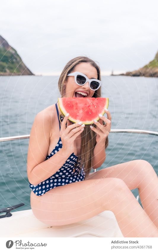 Junges Mädchen mit Brille und Badeanzug auf einem Segelboot isst ein Stück Wassermelone Frau Sommer Person Badebekleidung Spaß Glück Meer Jacht Sonnenbrille