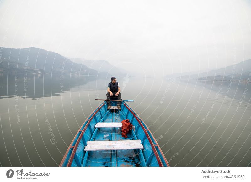 Reisender Mann schwimmt in Boot auf See in nebligem Morgen Schwimmer Nebel Teich Berge u. Gebirge männlich Nepal reisen Urlaub Wasser ruhig Windstille Dunst