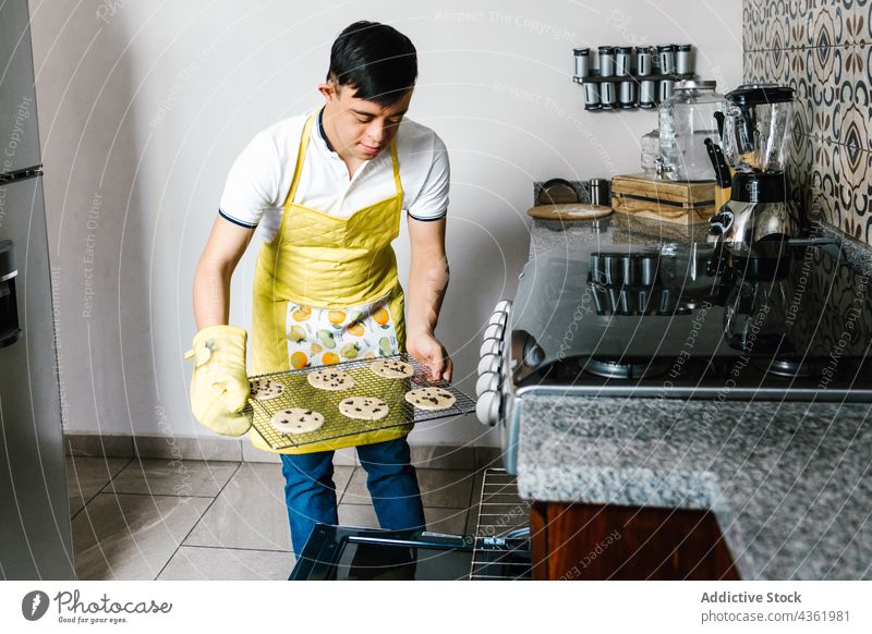 Lateinischer Teenager mit Down-Syndrom bereitet in der Küche Kekse zu Junge Koch Ofen vorbereiten Erkrankung mental Dessert ethnisch Gebäck süß backen