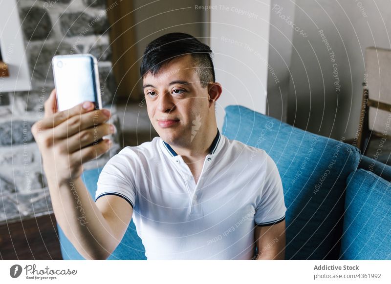 Ethnischer Teenager mit Down-Syndrom macht Selfie zu Hause Junge Lächeln Smartphone Selbstportrait Erkrankung heimwärts Gedächtnis Moment Glück ethnisch Latein