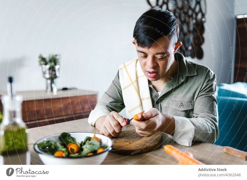 Lateinischer Junge mit Down-Syndrom kocht gemeinsam Salat Koch Salatbeilage Hilfsbereitschaft geschnitten Gemüse Mittagessen ethnisch Erkrankung deaktivieren