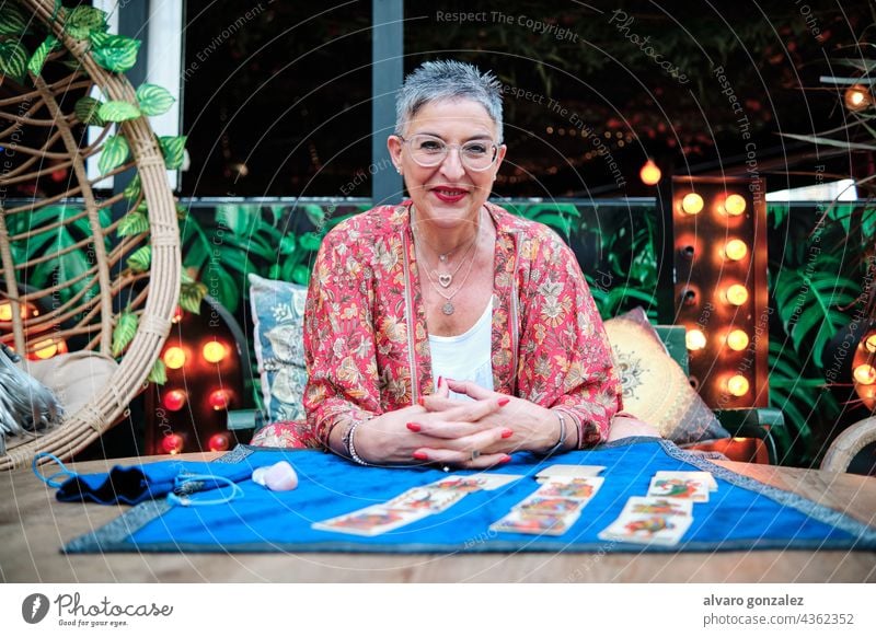 Reife Frau mit grauen Haaren benutzt Tarotkarten, um die Zukunft vorherzusagen Kaukasier Erwachsener Karten selbstbewusst reif Holunderbusch Hexe Vermögen