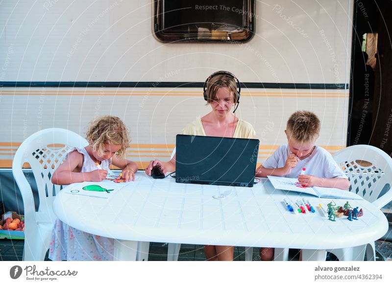 eine Familie in einem Wohnwagen auf einem Campingplatz. Die Mutter arbeitet und die Kinder malen in ihrer Freizeit Feiertag Sommer Business Arbeit Frau Menschen