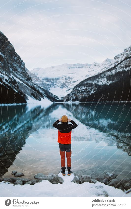 Unbekannter Tourist steht am Ufer eines ruhigen Sees Berge u. Gebirge bewundern Schnee Winter Windstille Wasser kalt Banff National Park Lake Luise Alberta