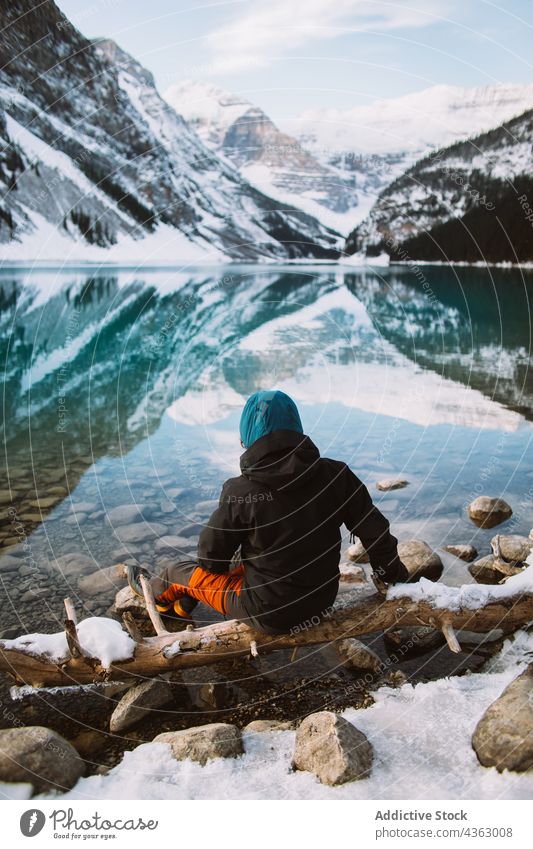 Unerkannter Reisender streckt die Arme in der Nähe eines ruhigen Sees aus Ufer ruhen Berge u. Gebirge Dehnung sitzen Natur Wasser Winter Lake Luise