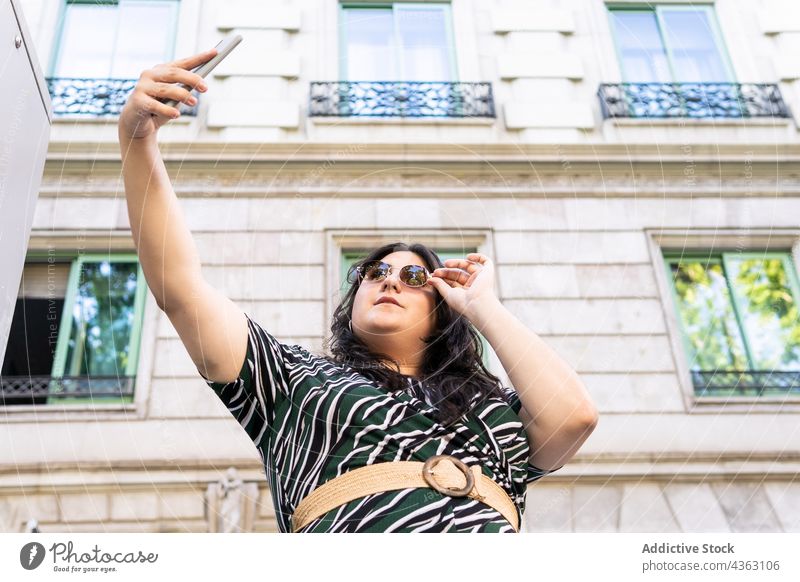 Stilvolle Frau nimmt Selfie in der Stadt urban Smartphone Sonnenbrille Kleid kurvenreich trendy Mode jung Übergröße Brille Outfit Aussehen Telefon fotografieren