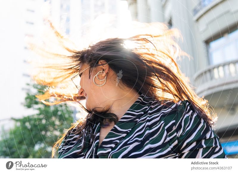 Stilvolle langhaarige Frau hat Spaß auf der Straße Behaarung Ohrringe Sonnenlicht Spaß haben Sommer urban Glück Mode jung Accessoire fliegendes Haar