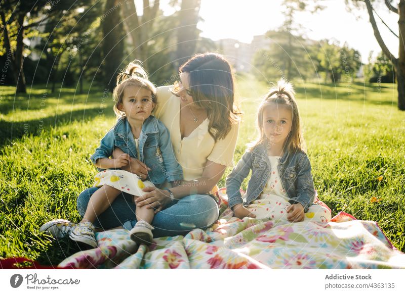 Mutter mit kleinen Töchtern ruht sich im Park aus Kind Zusammensein Sommer Geschwisterkind Liebe Glück Tochter ähnlich niedlich kuscheln Mama Partnerschaft