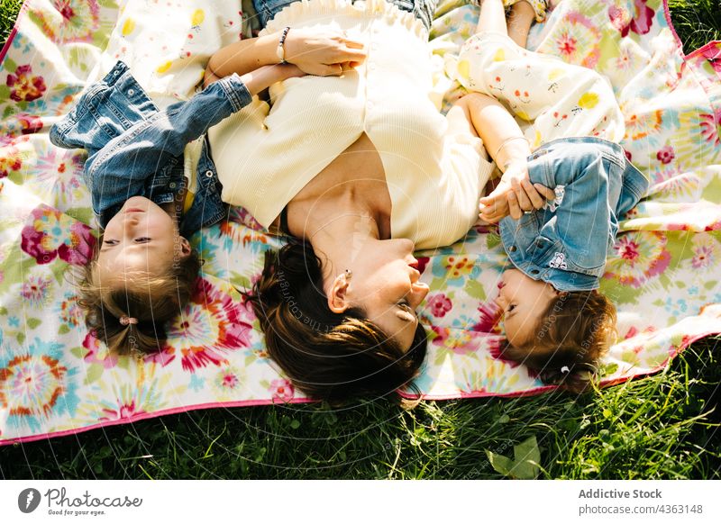 Kleine Geschwister mit Mama auf einer Decke im Park liegend Mutter Kind Zusammensein Glück Sommer Geschwisterkind Liebe Tochter ähnlich niedlich Partnerschaft