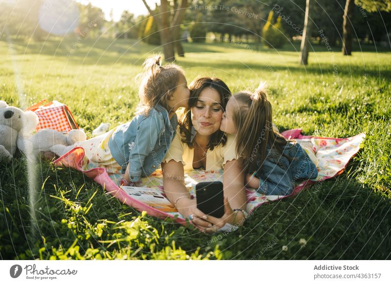Fröhliche Mutter und Kinder machen ein Selfie im Park Sommer Spaß haben Zusammensein Glück Smartphone Geschwisterkind heiter Liebe Mama Schwester zuschauen