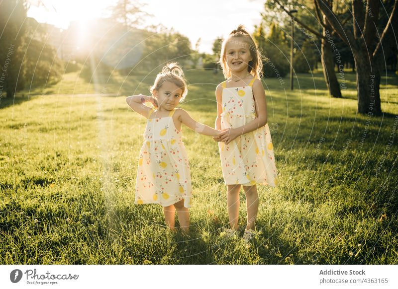 Glückliche kleine Geschwister in ähnlichen Kleidern im Sommerpark Mädchen Schwester Geschwisterkind Zusammensein Natur Kind Park Kinder Sonnenlicht grün