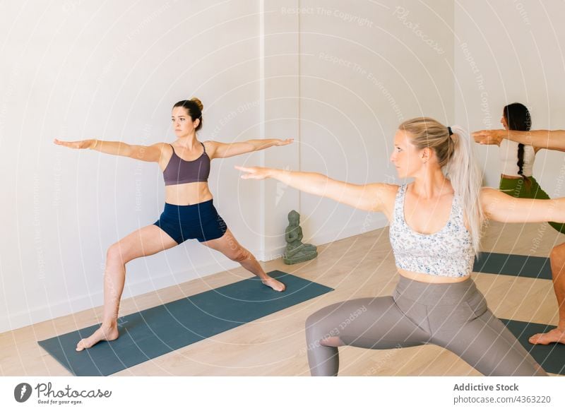 Frauen beim Yoga mit Lehrer im Studio Ausbilderin Menschengruppe Klasse üben Krieger-Pose Zusammensein Atelier Trainerin Zen Wohlbefinden Asana Unternehmen