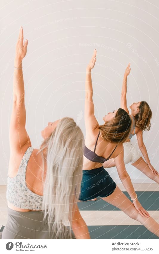 Gruppe von Frauen, die Yoga in Reverse Warrior Pose machen Klasse Menschengruppe Lektion Anmut umgekehrte Krieger-Pose Atelier Dehnung beweglich Zusammensein