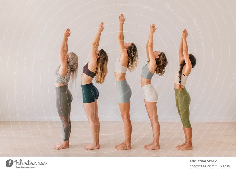 Gesellschaft von Frauen, die Yoga in Berghaltung mit erhobenen Armen machen Menschengruppe Klasse üben Berg-Pose Namaste Arme hochgezogen Atelier Lektion