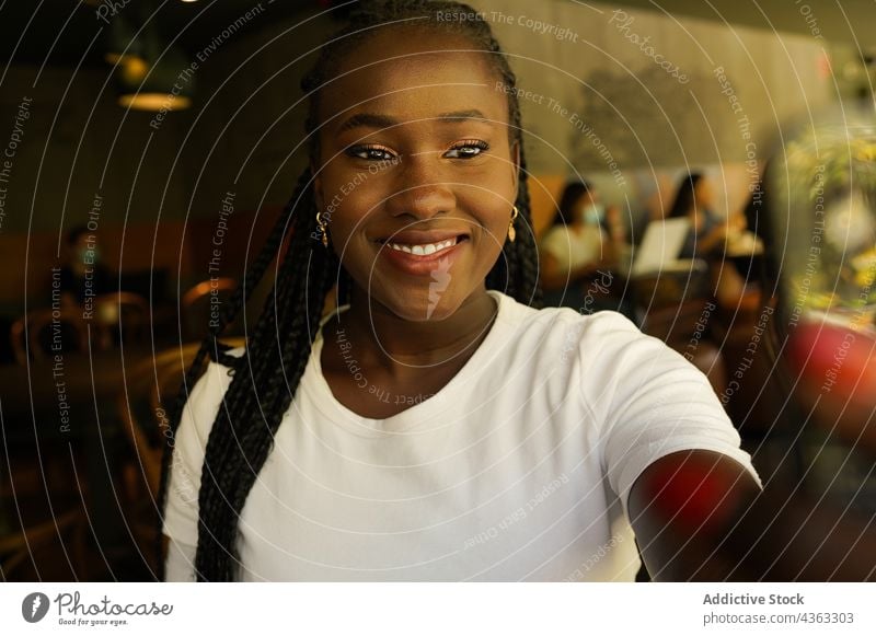 Schwarze Frau macht Selfie im Café heiter Lächeln Selbstportrait Geflecht Kälte unterhalten Spaß haben ethnisch schwarz Afroamerikaner benutzend charmant