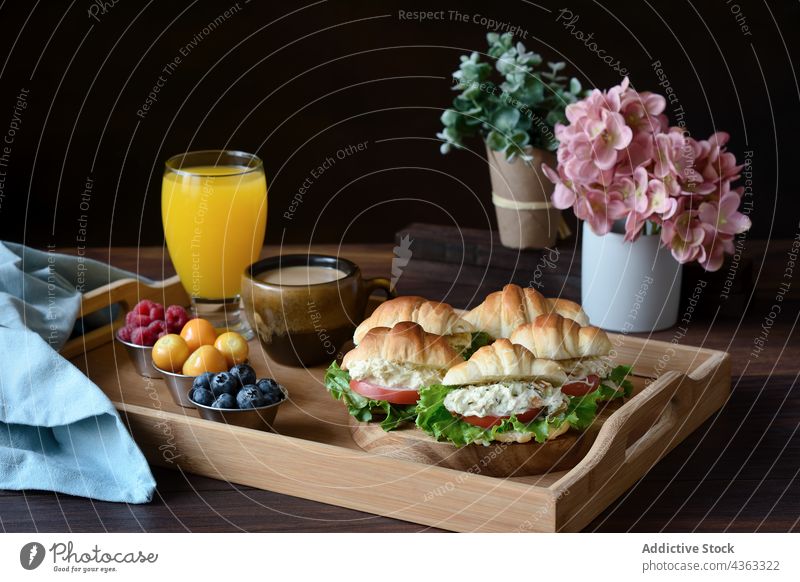 Appetitliches französisches Frühstück mit Croissant-Sandwiches auf dem Tablett Belegtes Brot Lebensmittel Saft Kaffee geschmackvoll dienen Tisch lecker frisch
