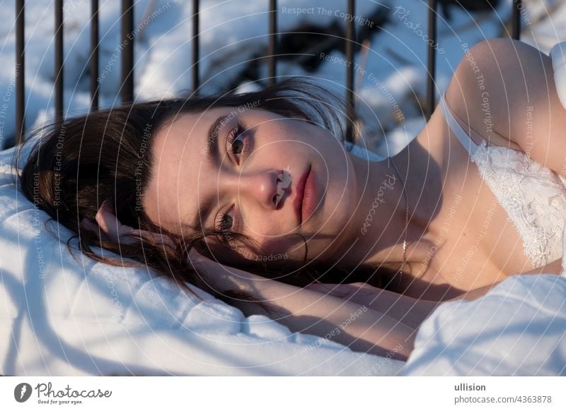 Porträt einer attraktiven, jungen, sexy, verführerischen Frau im Bett, in weißer Nachtwäsche, Kopf auf der Hand schlafen Morgen Sonne Ansicht dunkel braun