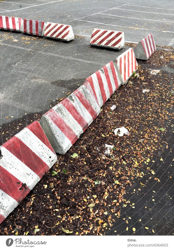 Zwischenräume | Löcher im System stein straßensperren laub parkplatz beton betonschranke barriere rot weiß gestrichen abgegrenzt markiert rechteck trashig
