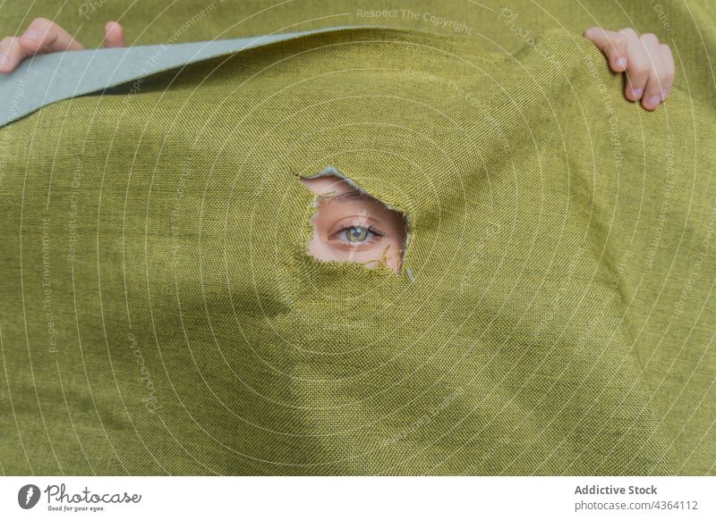 Frau mit grünen Augen schaut durch ein Loch im Stoff grüne Augen Farbe Starrer Blick starren Tierhaut Golfloch Mysterium Schönheit Deckblatt jung feminin gucken