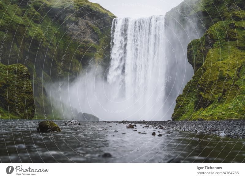 Der wunderschöne Wasserfall Skogafoss. Das beliebteste Ausflugsziel in Island. Wasser fällt ein schönes Tal hinunter und spiegelt sich im Fluss darunter Nebel