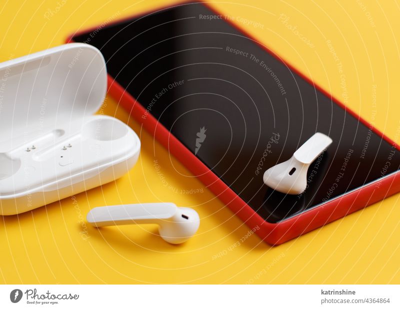 Smartphone und drahtlose Kopfhörer mit geöffnetem Gehäuse auf gelbem Hintergrund Drahtlos Fall Attrappe weiß rot abschließen Zubehör Mobile Telefon Handy
