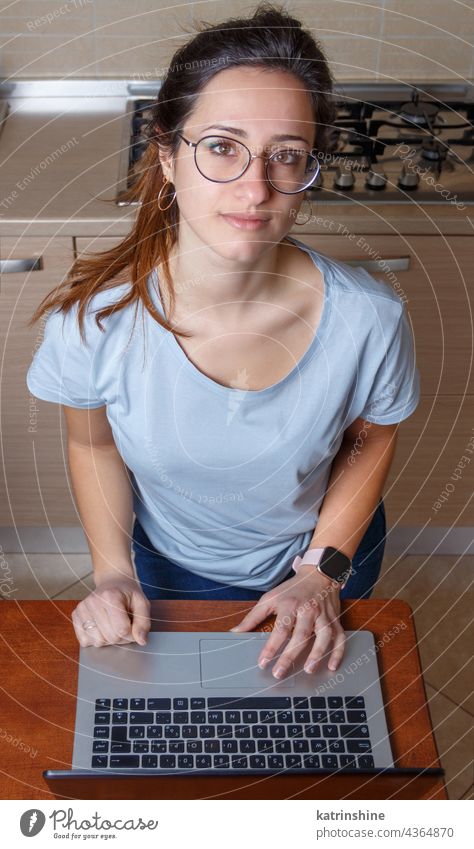 Junge Frauen mit Laptop in der Küche zu Hause jung Attrappe T-Shirt Tippen lernen Schüler Lifestyle Brille ernst konzentriert im Innenbereich Lächeln Rundhals