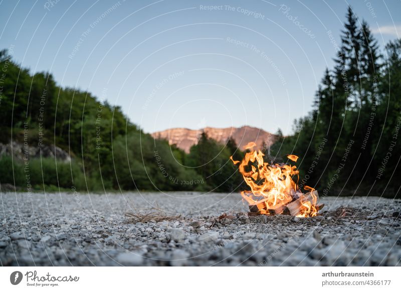 Lagerfeuer im steinigen Flussbett in der Natur bei den Bergen natur wald Naturerlebnis Naturliebe waldgebiet Waldrand Berge im Hintergrund sonnenlicht