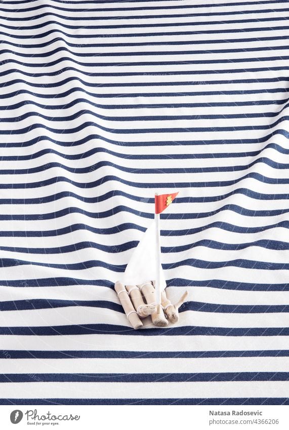 Holzfloß mit weißen Segeln auf dem Hemd eines Seemanns anstelle des Meeres. Hintergrund Sommer Konzept abstrakt marin Zeitgenosse Rechteck hölzern Ästhetik