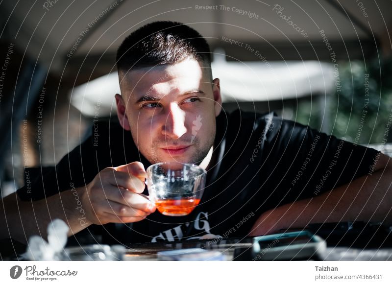 Nahaufnahme eines Mannes beim Teetrinken in einem Cafe Person Blick männlich Sitzen Kaukasier heiter Becher Tasse allein abschließen Genuss modisch Finger Typ