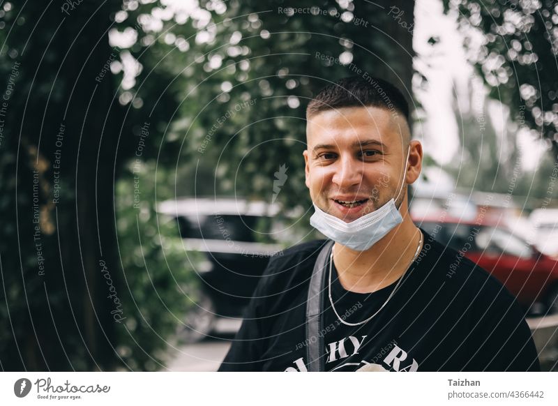 Junger Mann mit modischem Haarschnitt, der eine medizinische Maske von seinem Gesicht entfernt hat und lächelt. Nahaufnahme Porträt Coronavirus Freude