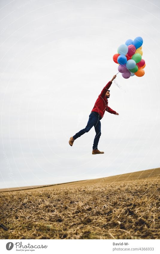 abheben und losfliegen - Mann hält sich an Luftballons fest Himmel träumen schweben Spaß hoch Freiheit Traum Wunsch Leichtigkeit frei aufsteigen bunt
