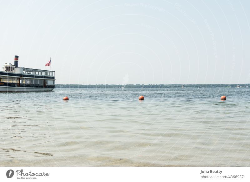 Touristenboot auf dem Wasser eines Sees im Mittleren Westen der USA; ruhiges Wasser mit Bojen an einer Leine zur Abgrenzung des Badebereichs im Vordergrund