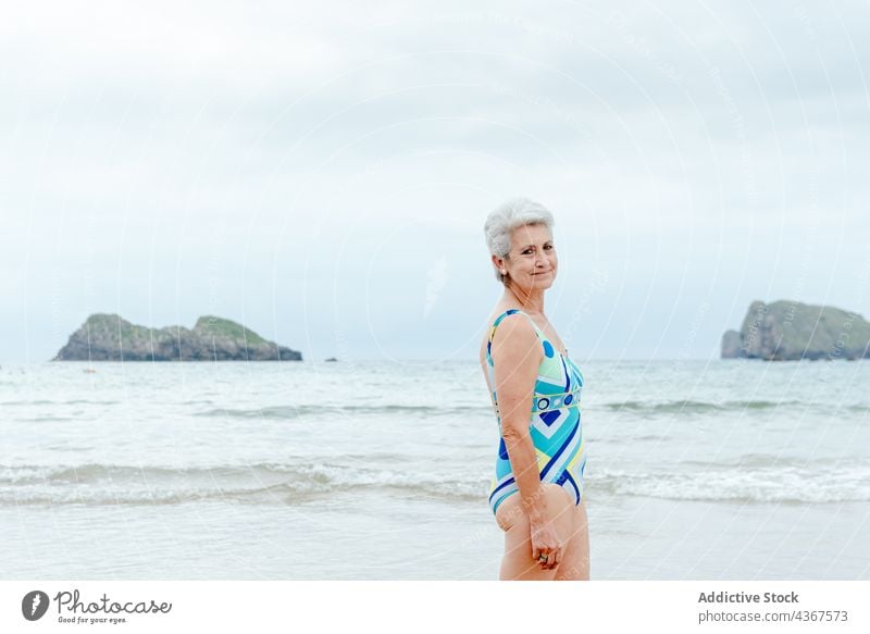 Ältere Frau im Badeanzug ruht sich am Strand aus Senior Lächeln MEER Meer Sommer Glück Stil gealtert graues Haar in den Ruhestand gehen ruhen winken