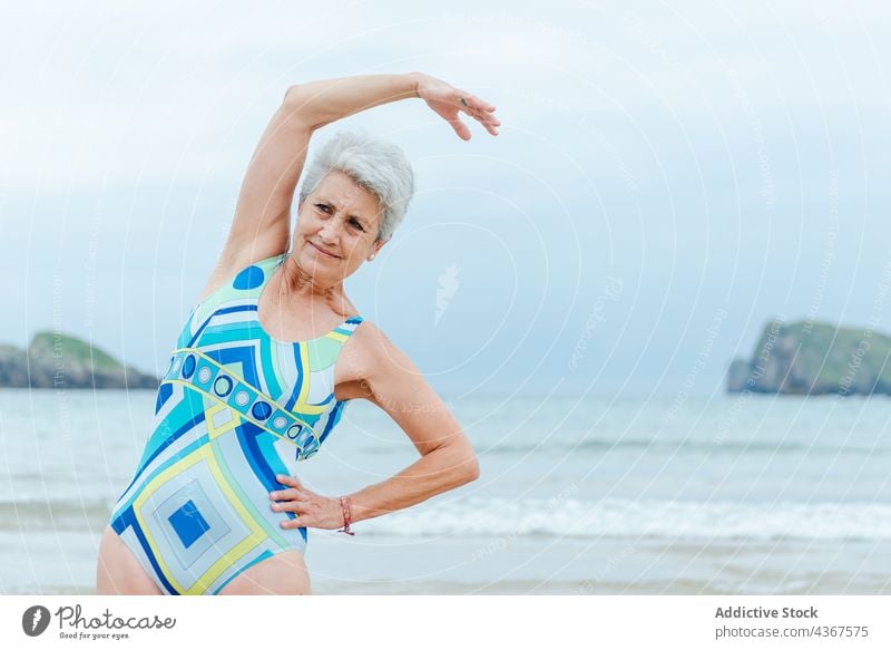 Alte Frau macht Übungen am Strand Senior Training Gesunder Lebensstil positiv Badeanzug MEER Stil Aktivität graues Haar alt Meer Lifestyle farbenfroh