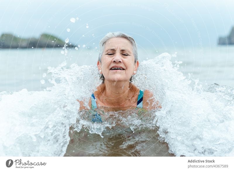 Alte Frau schwimmt im Meerwasser Senior schwimmen MEER Strand Wasser aktiv Sommer Gesunder Lebensstil alt gealtert graues Haar genießen Bad Lifestyle üben Natur