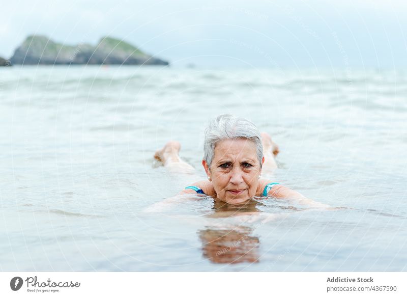 Alte Frau schwimmt im Meerwasser Senior schwimmen MEER Strand Wasser aktiv Sommer Gesunder Lebensstil alt gealtert graues Haar genießen Bad Lifestyle üben Natur