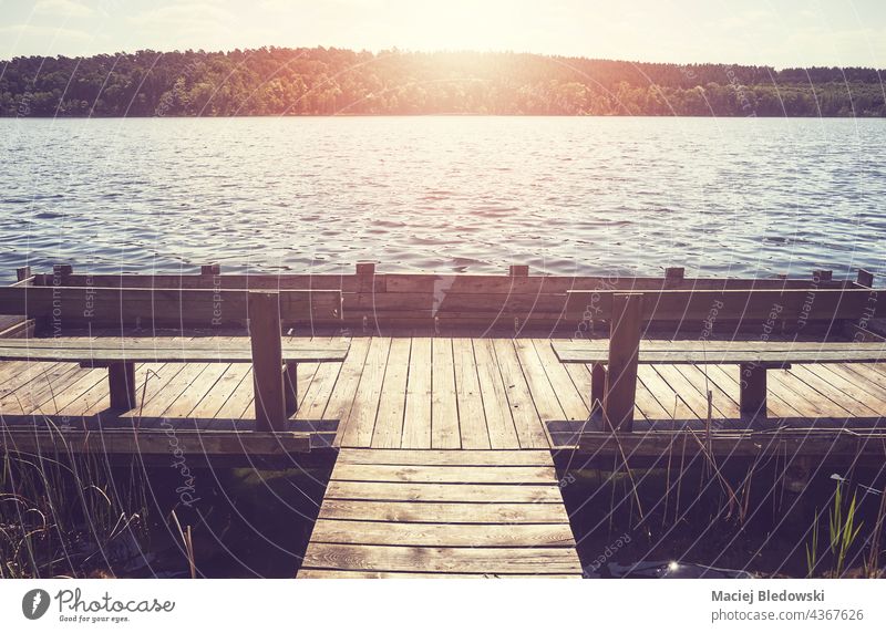 Holzsteg mit Bänken an einem See in der Sonne, farbig getönt. Natur Pier friedlich retro Wasser Bank hölzern Podest Urlaub ruhig malerisch Feiertag